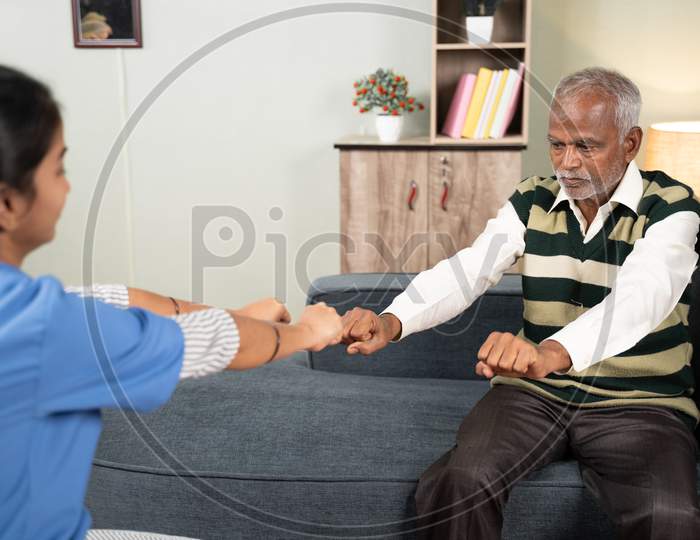 Physician Doctor Or Nurse Helping Sick Senior Man Todo Exercise At Home During Home Health Visit.
