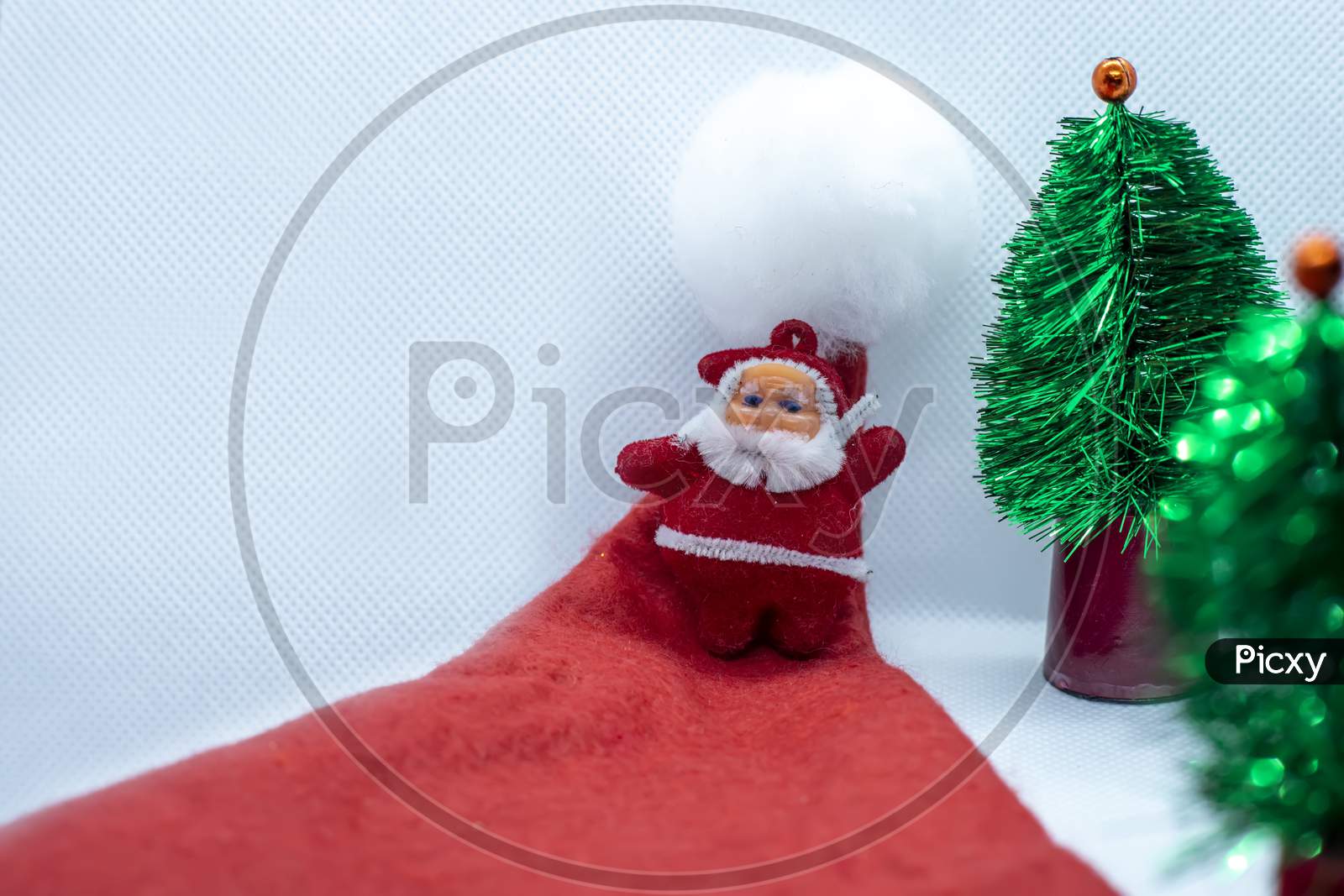 Santa Claus Stands In A Santa Claus Hat Near A Tree On A White Background