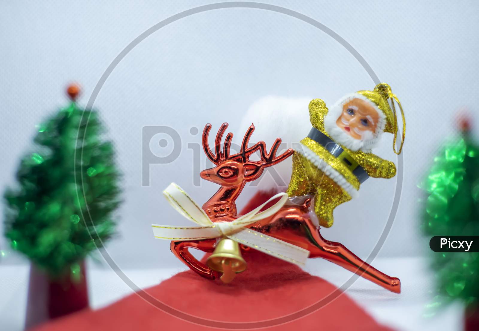 Santa Claus On A Deer Traveling In A Santa Claus Hat Near A Tree On A White Background