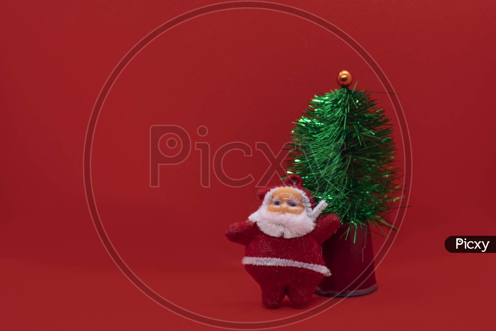 Christmas Tree With Santa Claus On Red Studio Background. Holiday Festive Celebration Greeting Card With Copy Space
