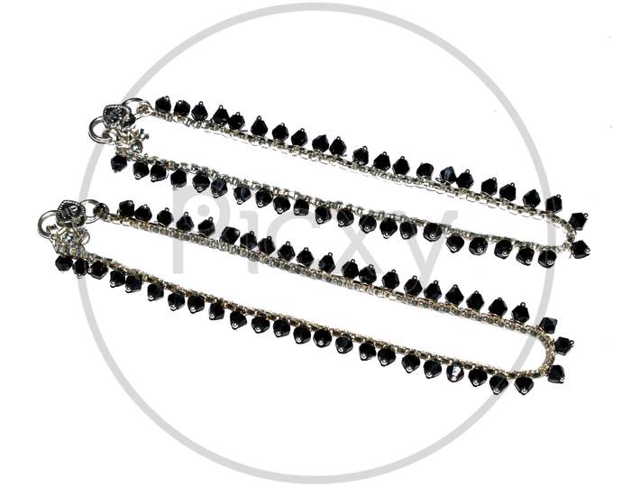 Women anklets pair designed with black stones isolated on white.