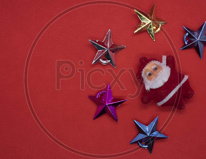 Christmas Composition. Top View Santa Claus Surrounded By Colorful Stars On A Red Background. Flat Lay, Top View, Copy Space