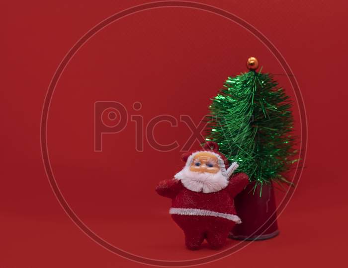 Christmas Tree With Santa Claus On Red Studio Background. Holiday Festive Celebration Greeting Card With Copy Space