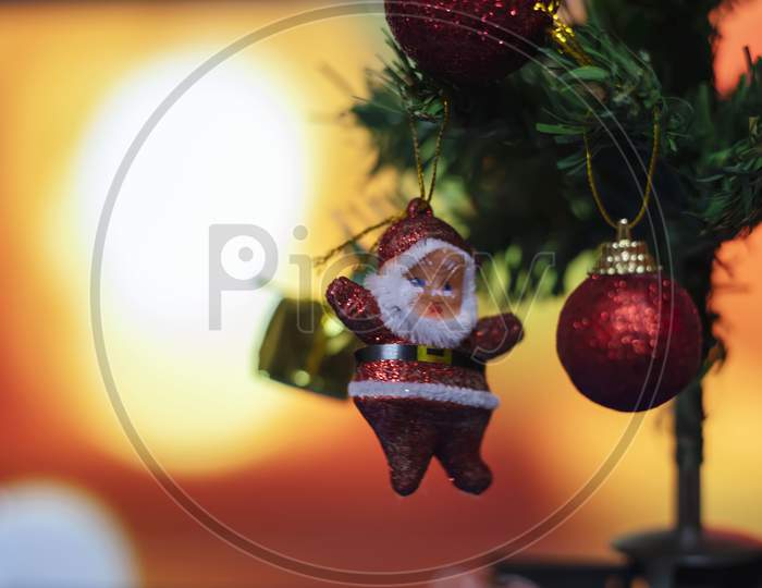 Merry Christmas And Happy New Year Concept, Closeup Of Sanda Clause Hanging From A Decorated Tree With Bokeh, Xmas Holiday Background.