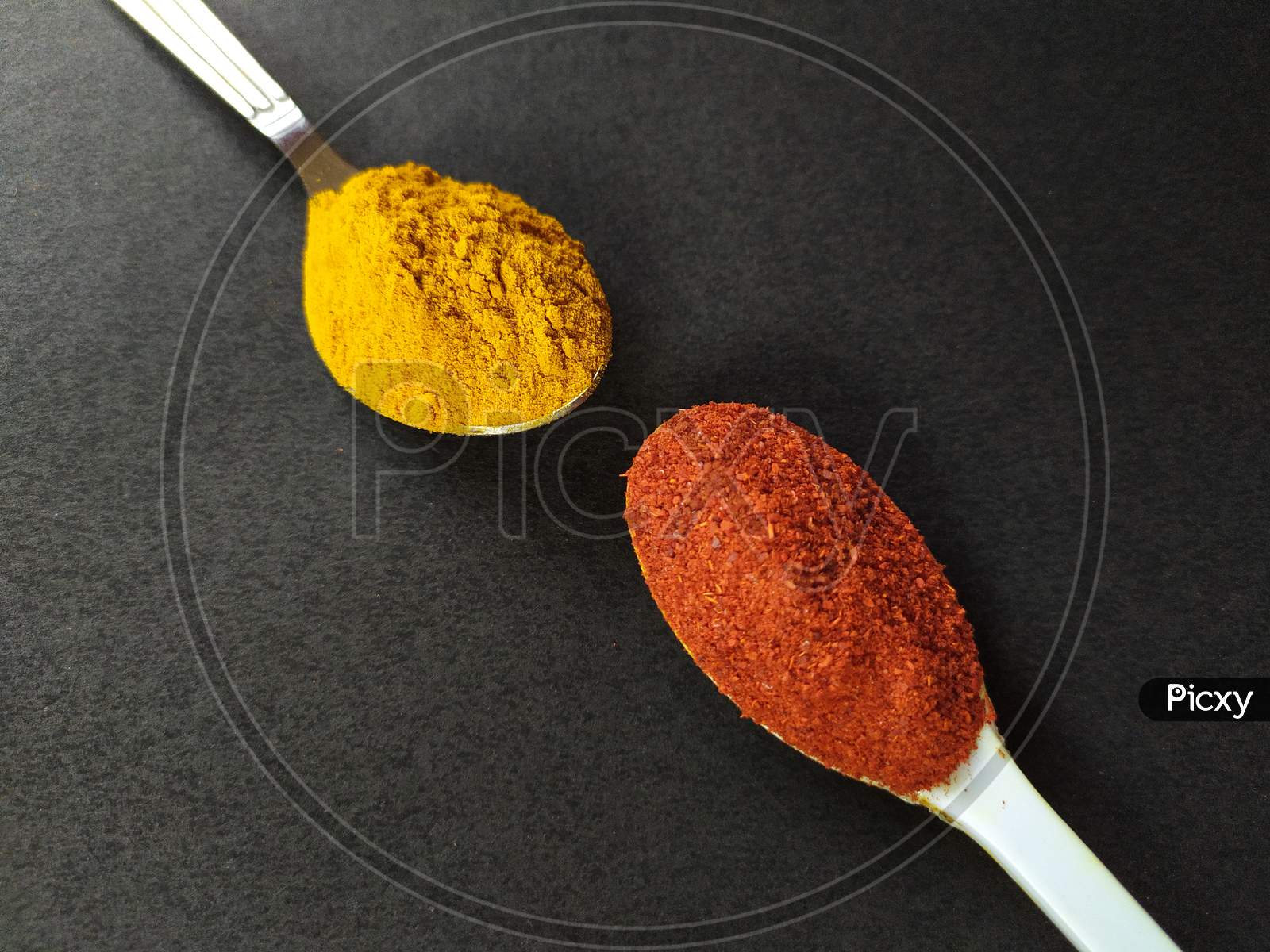 Cooking spices, turmeric and red chilli powder on black background.