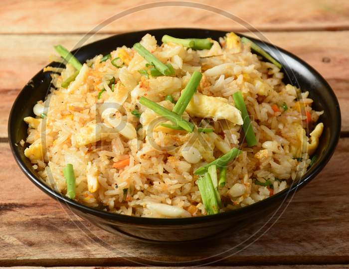 Indian Cuisine Healthy And Tasty Brunt Garlic Chicken Fried Rice Served In Black Bowl Over A Rustic Wooden Background, Selective Focus