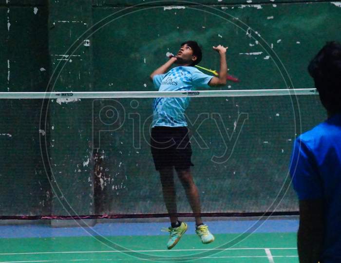 Image of new badminton player attempting jump smash in multi shuttle strokes practice