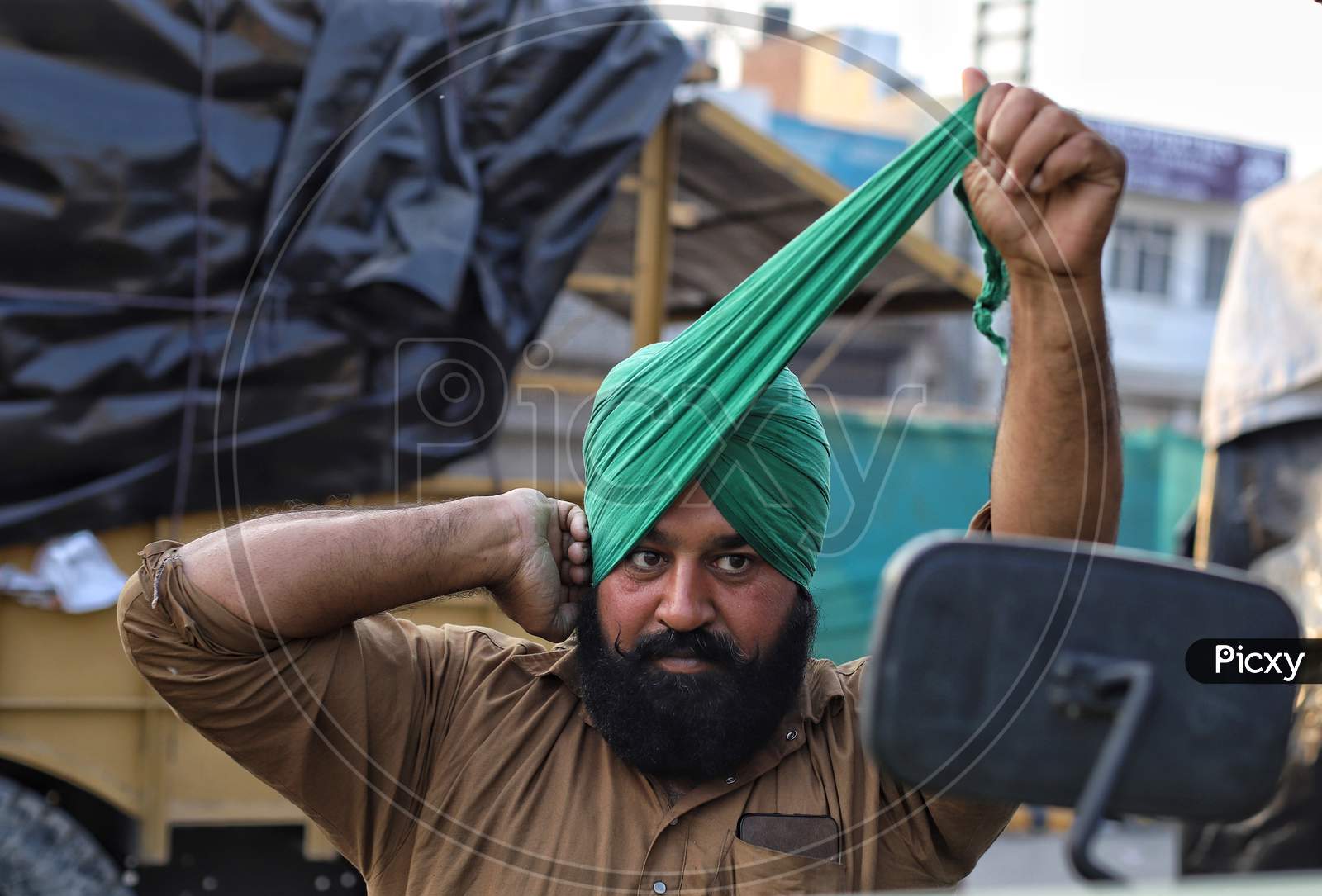 A Sikh farmer ties his turban during a farmers protest at Singhu Border. Thousands of farmers are protesting against  new farm laws at various entry points of New Delhi, India.