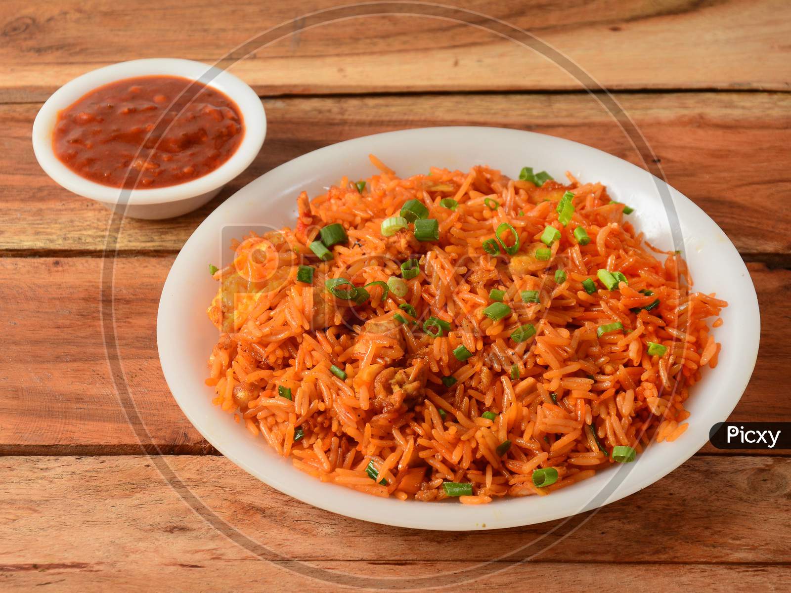 Tasty Schezwan Chicken Fried Rice With Tomato Sauce Served In White Bowl Over A Rustic Wooden Background, Indian Cuisine, Selective Focus