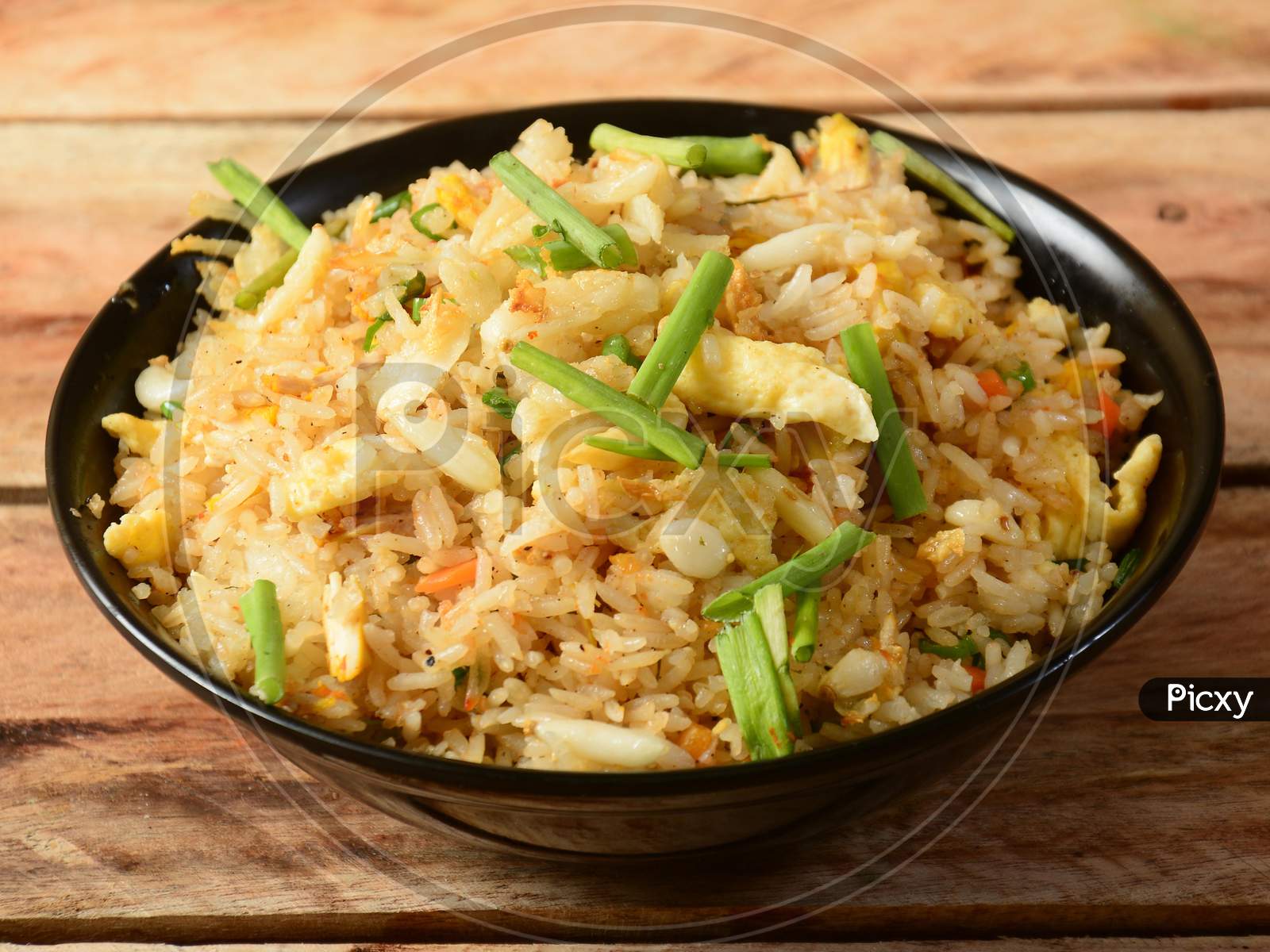 Indian Cuisine Healthy And Tasty Brunt Garlic Chicken Fried Rice Served In Black Bowl Over A Rustic Wooden Background, Selective Focus