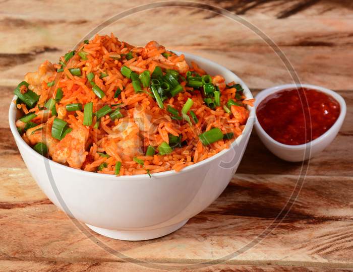Tasty Schezwan Chicken Fried Rice With Tomato Sauce Served In White Bowl Over A Rustic Wooden Background, Indian Cuisine, Selective Focus