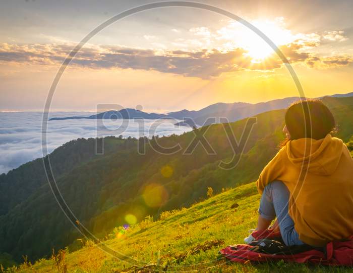 Female Person Sits And Enjoys The Views Of Stunning Landscape Above The Clouds In Gomismta. Georgia Travel Destination