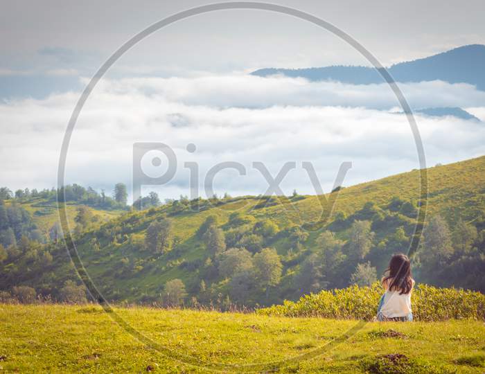 Woman Sits In Distance With Stunning Natural Summer Nature Around Above The Clouds. Summer In Georgia.