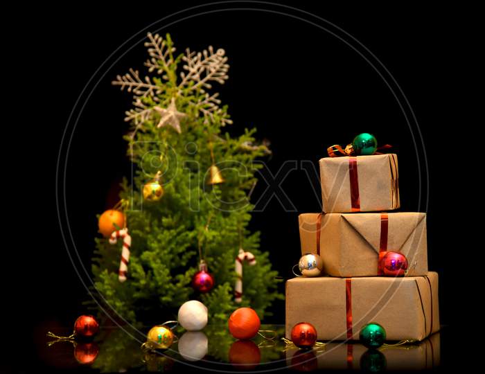 christmas tree with colorful balls and gift boxes over dark background