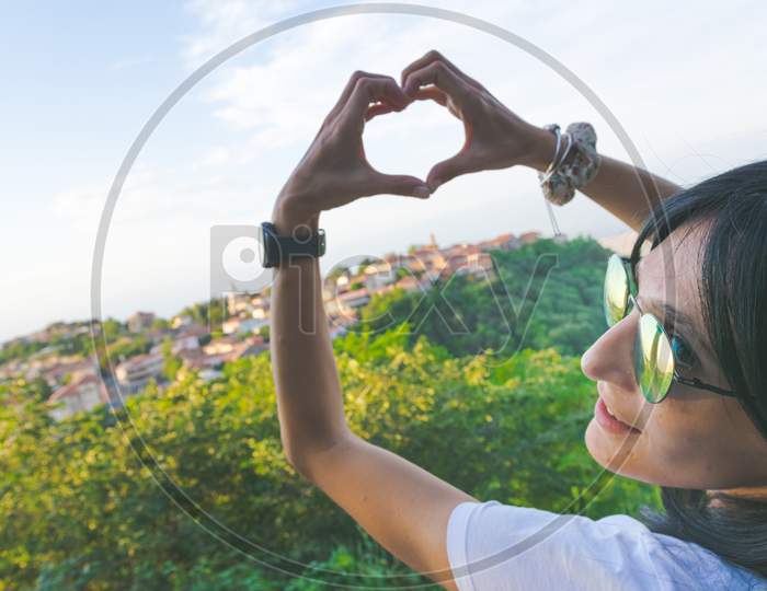Attractive Caucasian Woman Forms Heart With Hands With Beautiful Sighnaghi City Panorama.