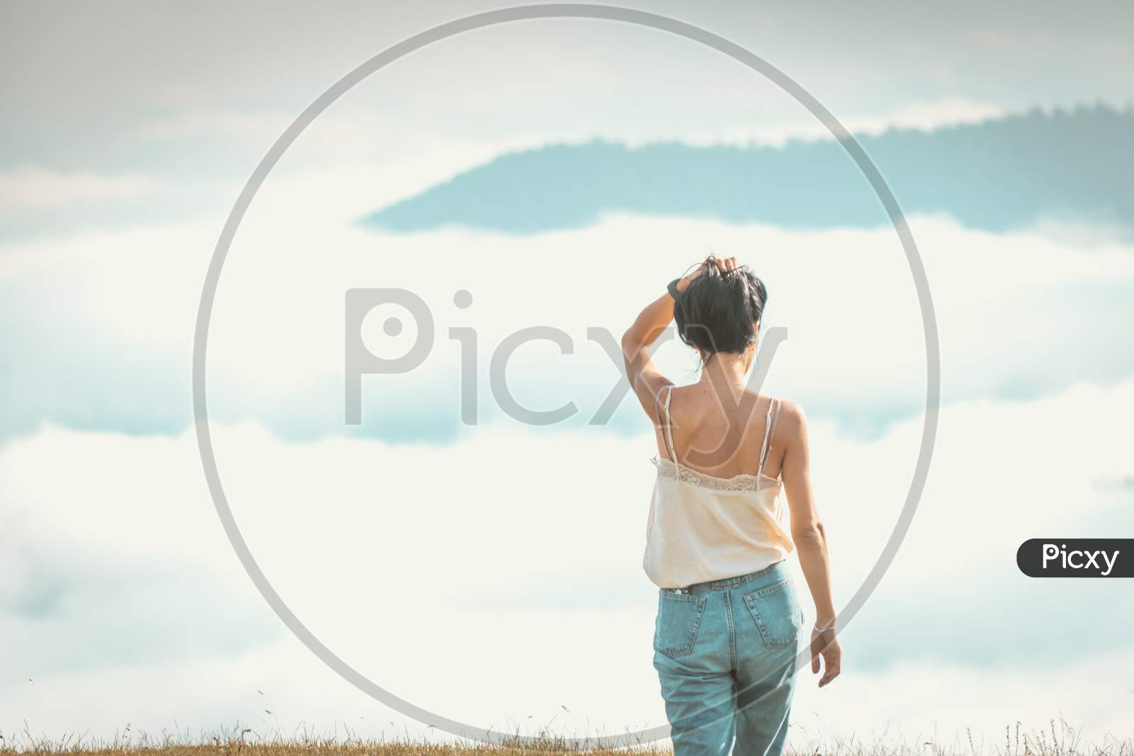 Woman Relaxed Walks Towards The Cloudscape In Pristine Nature. Concept Of Freedom And Life