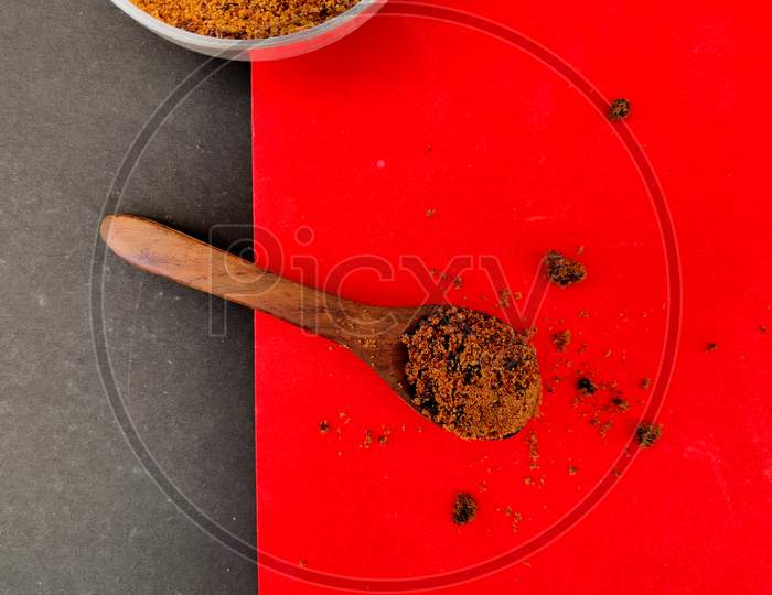 Brown Sugar In Wooden Spoon.Isolated On Red And Black Background