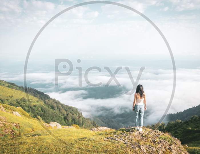 Solo Brunette Woman Relaxed Stands On The Edge Above Clouds Carefree Lifestyle. Adventure And Fullflment In Life Concept.
