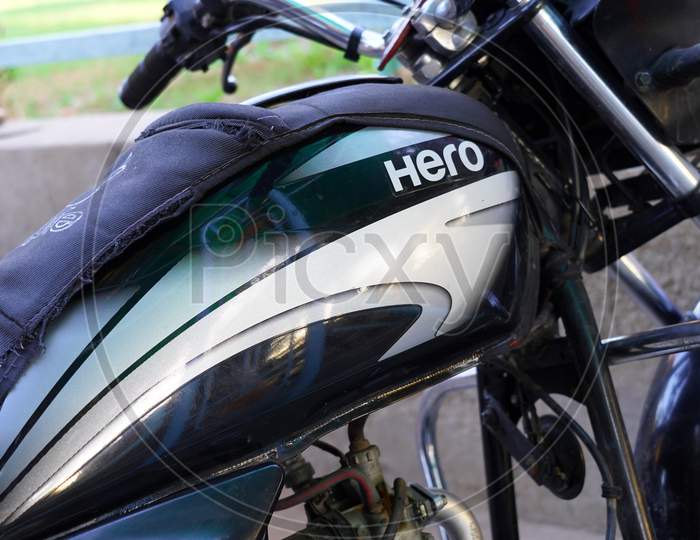 Alluring Ornamented Hero Logo View On The Motorcycle. Attractive Side View Hero Logo On The Fuel Tank With Bold Font Style.