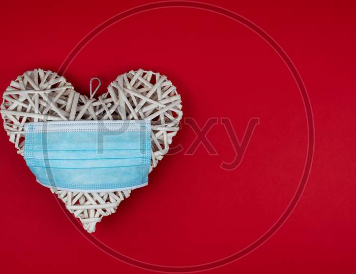 White Heart With A Blue Face Mask On A Red Background. Concept Of A Valentine´S Day During Coronavirus Or Covid Pandemic.