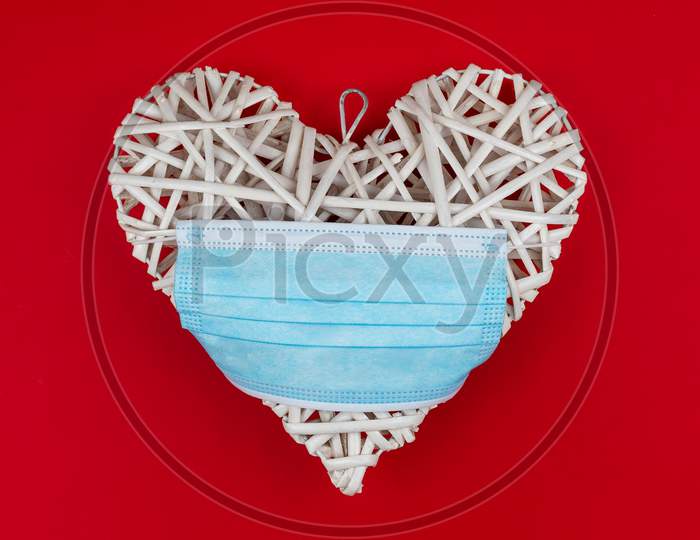 White Heart With A Blue Face Mask On A Red Background. Concept Of A Valentine´S Day During Coronavirus Or Covid Pandemic.