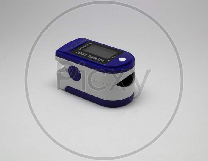 Blue and white portable Pulse Oximeter sensor to monitor oxygen level of a person and pulse rate of a person with white background and selective focus
