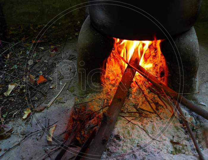 Selective Focus On Rural Hand Made Stove With Heating Bowl View. Red Flames View In The Stove. Water Steam Emerging From Bowl.