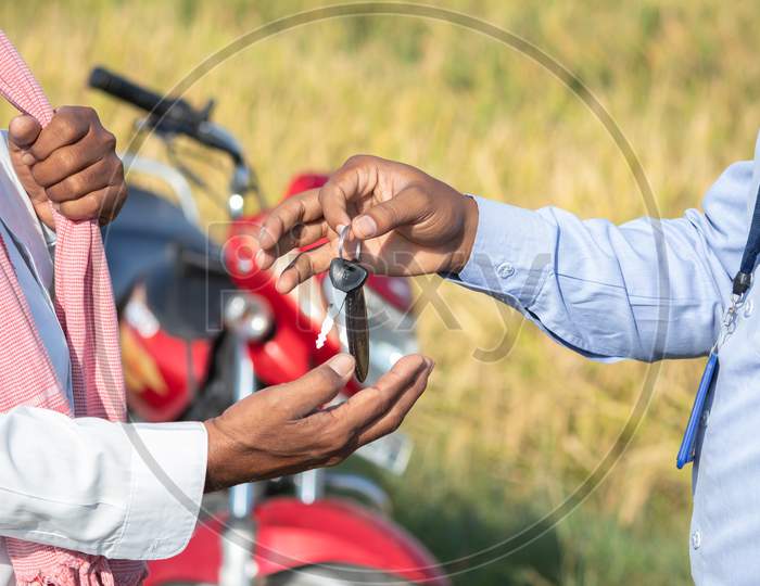 Close Up Of Farmer Hands Receiving Keys From Banker Or Corporate Officer - Concept Of Farmer Bike Or Two Wheeler Loan.
