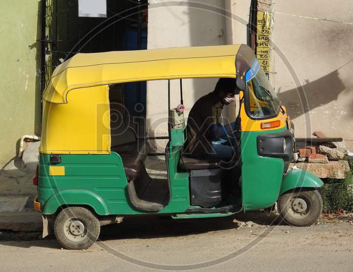 Green And Yellow Color Auto Rickshaw Parking On Roadside Of The Bangalore, Driver Sitting Inside.