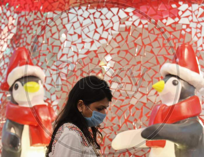 A woman wearing a protective mask walks past Christmas decorations inside a mall, amid the spread of the coronavirus disease (COVID-19) in Mumbai, India, December, 2020.