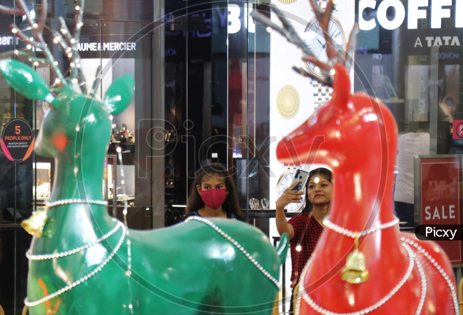 People wearing protective masks walk past Christmas decorations inside a mall, amid the spread of the coronavirus disease (COVID-19) in Mumbai, India, December, 2020.