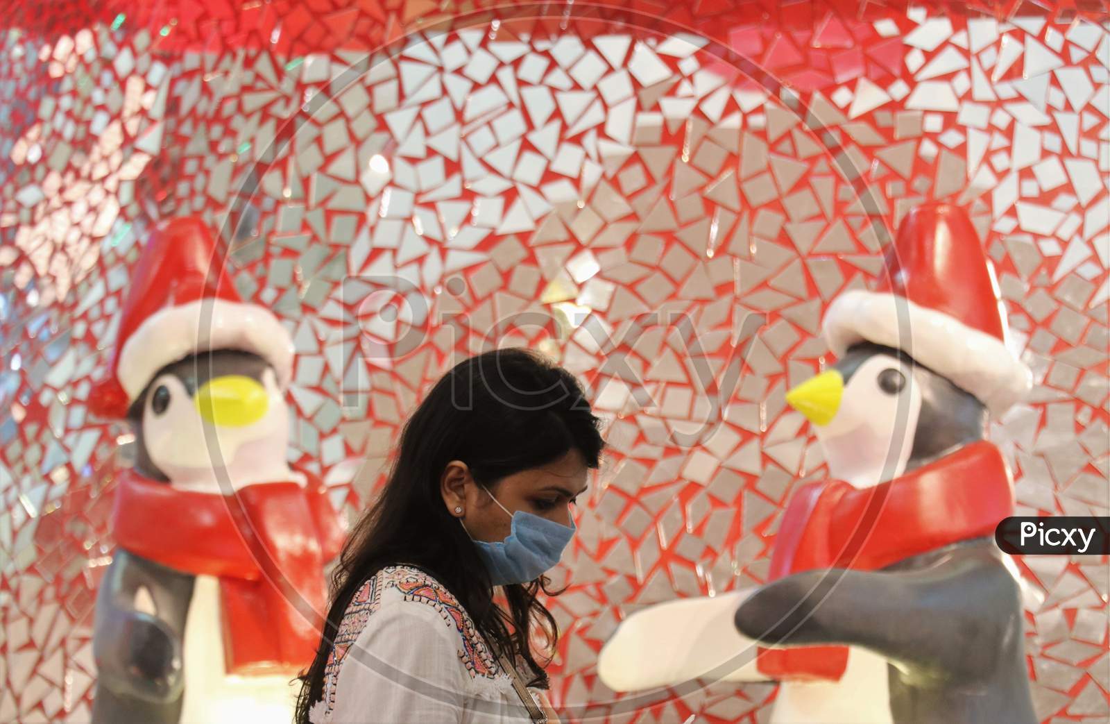 A woman wearing a protective mask walks past Christmas decorations inside a mall, amid the spread of the coronavirus disease (COVID-19) in Mumbai, India, December, 2020.