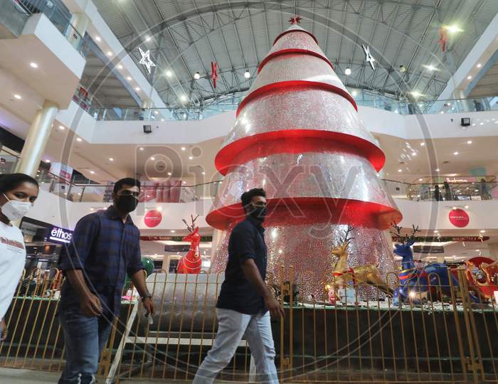 People wearing protective mask walk past Christmas decorations inside a mall, amid the spread of the coronavirus disease (COVID-19) in Mumbai, India, December, 2020.