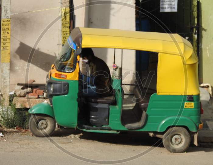 Green And Yellow Color Auto Rickshaw Parking On Roadside Of The Bangalore, Driver Sitting Inside.