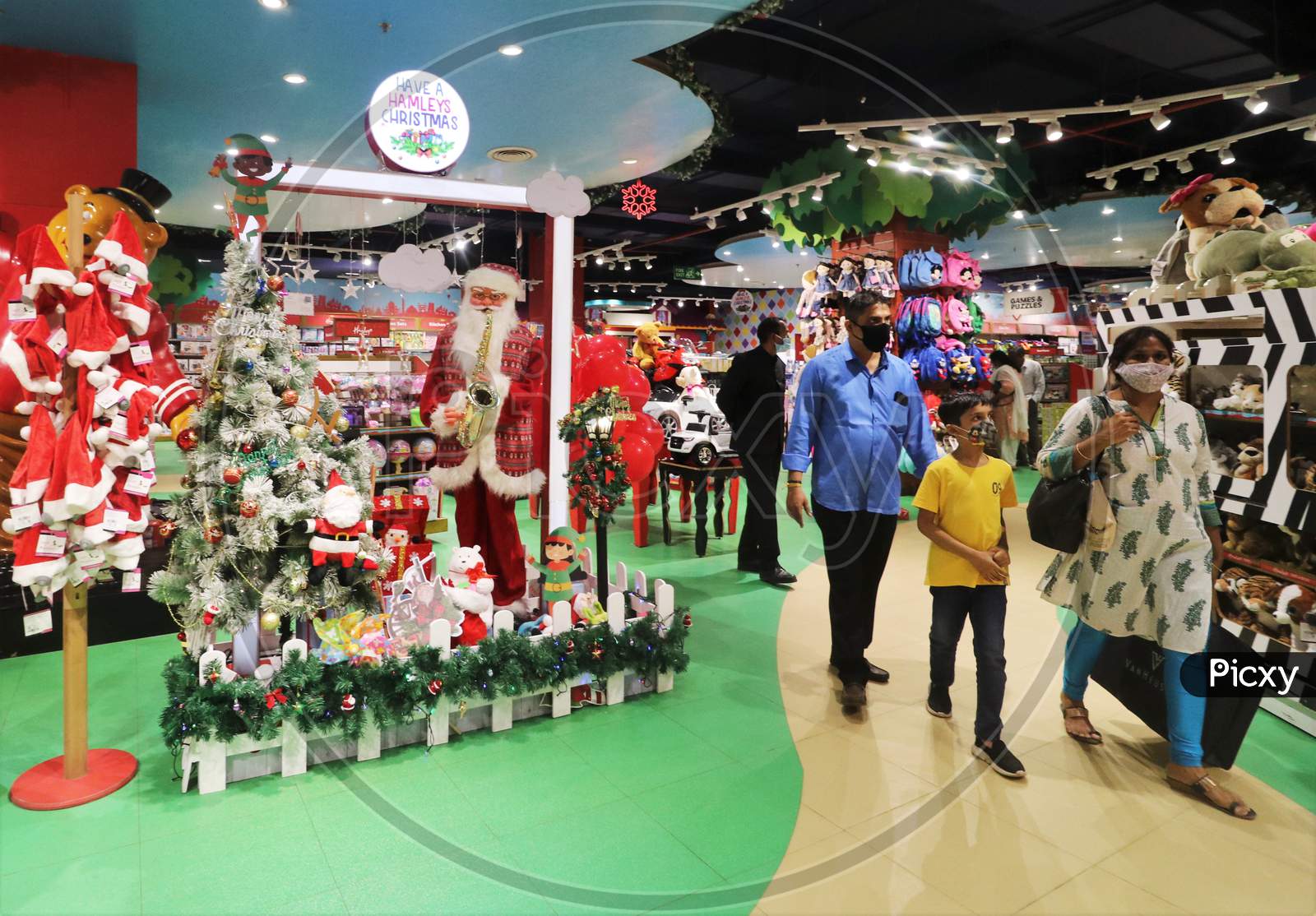 People wearing protective mask walk past Christmas decorations inside a mall, amid the spread of the coronavirus disease (COVID-19) in Mumbai, India, December, 2020.