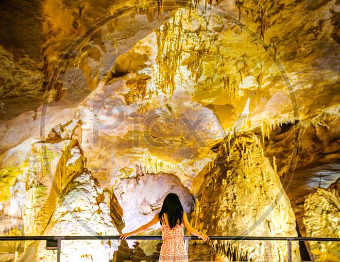 Back Side Female Person Stands On The Platform And Looks Up To Stunning Stalagmite Formations In Prometheus Cave. Georgia Travel Destination