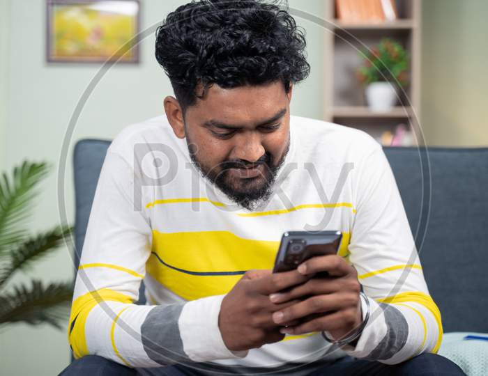Young Man Smiling By Reading Funny Message Or Sms On Mobile Phone - Concept Of Using Social Media, Internet And Entertainment Lifestyle.