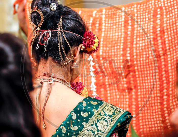 a scene from an Indian wedding from behind the bride during the varmala rituals