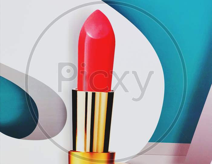 Red lipstick isolated with White and blue background with golden colour coted cover only one lipstick woman cosmetic item beauty product. Lip gloss hd quality.