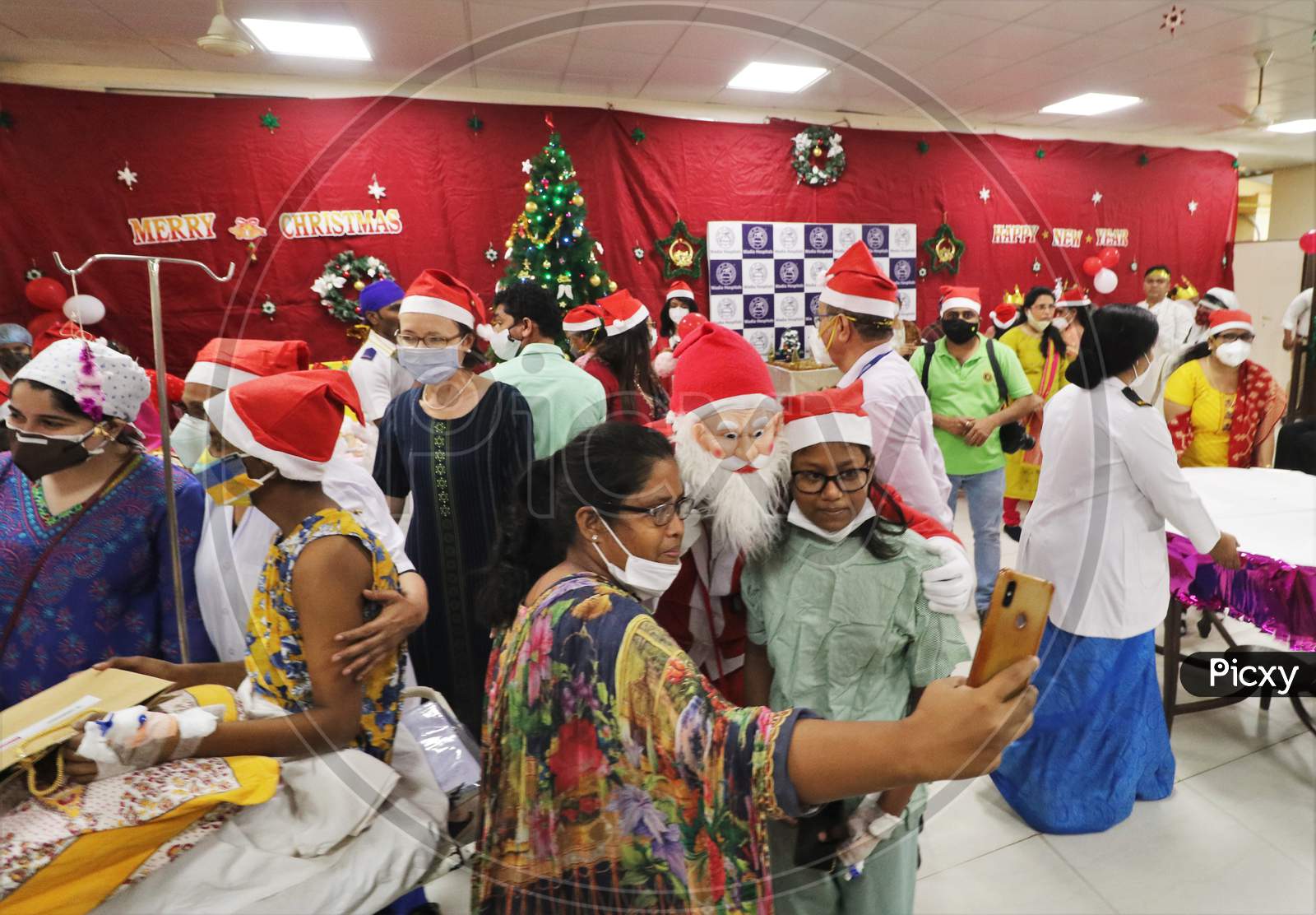 Parents of the patients take pictures with the man dressed as Santa Claus entertains patients during Christmas celebration, at  Wadia Hospital For Children in Mumbai, India on December, 2020.