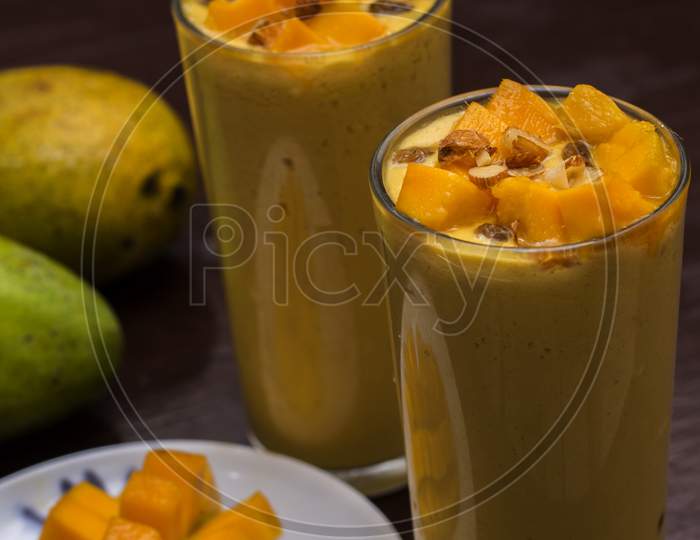 Mango Lassi Decorated With Mango Pulp Raisin Almonds And Ripe Mango In Background Mango Slice In Foreground