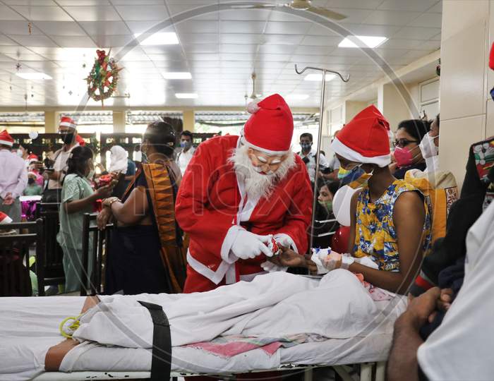 A man dressed as Santa Claus gives chocolate to a patient during Christmas celebration, at Bai Jerbai Wadia Hospital For Children in Mumbai, India on December, 2020.
