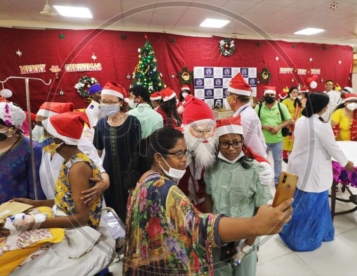 Parents of the patients take pictures with the man dressed as Santa Claus entertains patients during Christmas celebration, at  Wadia Hospital For Children in Mumbai, India on December, 2020.