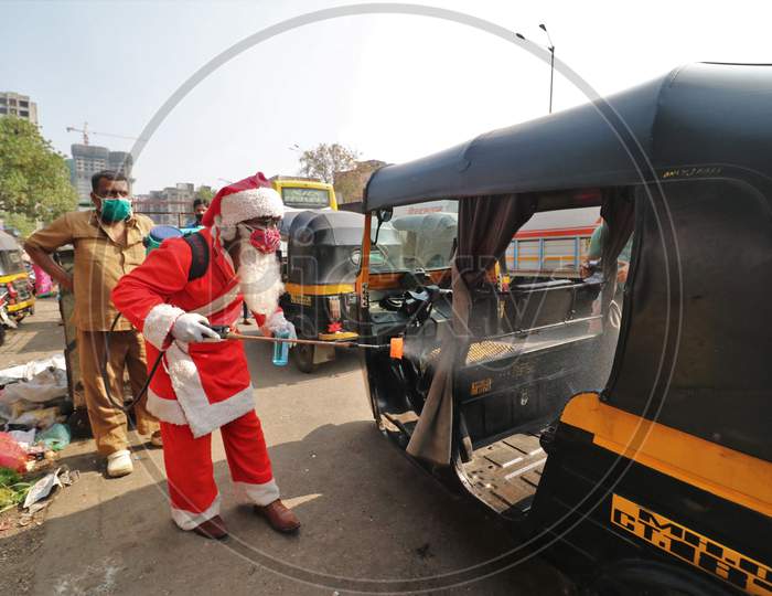 A man wearing a Santa Claus costume sanitizes an auto rickshaw, amidst the spread of the coronavirus disease (COVID-19), in Mumbai, India, December, 2020.