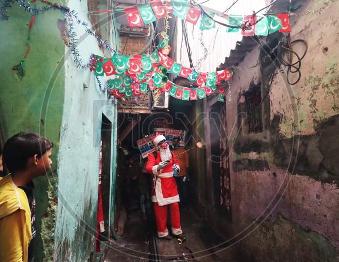 A man wearing a Santa Claus costume sanitizes the entrance of a house inside a slum, amidst the spread of the coronavirus disease (COVID-19), in Mumbai, India, December, 2020.