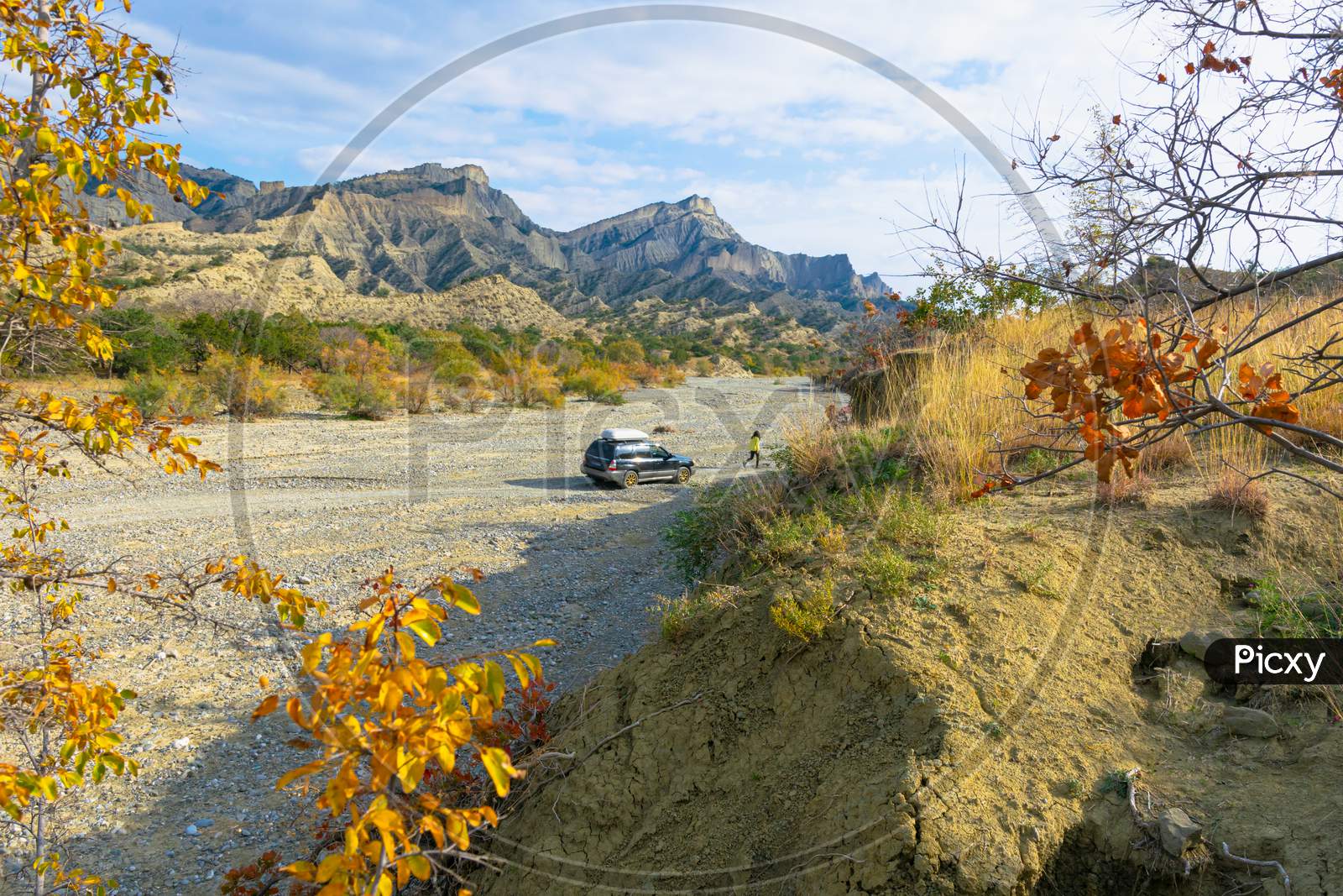 Person Walks From The 4Wd Car On Dry River Road Surounded By Autumn Nature And Stunning Landscape In Vashlovani National Park