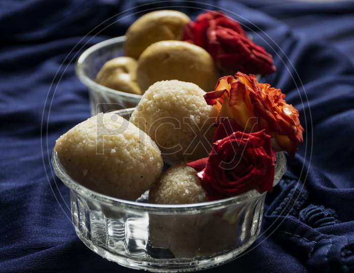 Picture Of Delicious Rawa Laddu Decorated In Bowl With Fresh Red Roses In A Blue Background. Rawa Laddus Made During Diwali Festival In India.