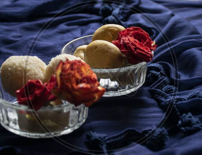Picture Of Delicious Besan Laddu Decorated In Bowl With Fresh Red Roses In A Blue Background. Besan Laddus Made During Diwali Festival In India.