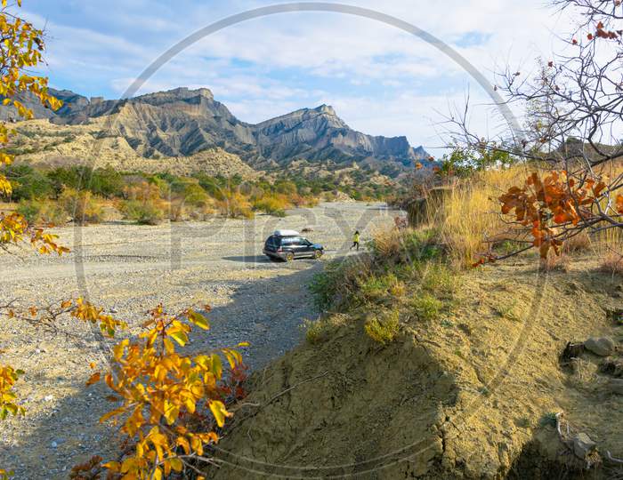 Person Walks From The 4Wd Car On Dry River Road Surounded By Autumn Nature And Stunning Landscape In Vashlovani National Park