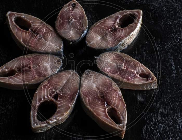 Slices Of Hilsha Fish On A Black Wooden Background